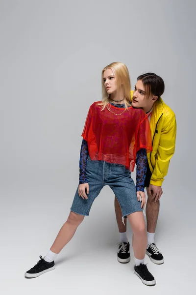 Giovane coppia alla moda guardando lontano su sfondo grigio — Foto stock
