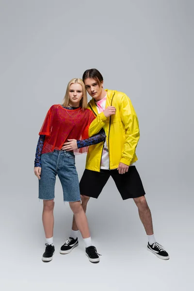 Молода пара в модному одязі позує на сірому фоні — стокове фото