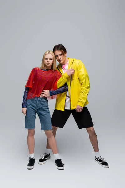 Pareja joven en ropa de moda posando sobre fondo gris - foto de stock