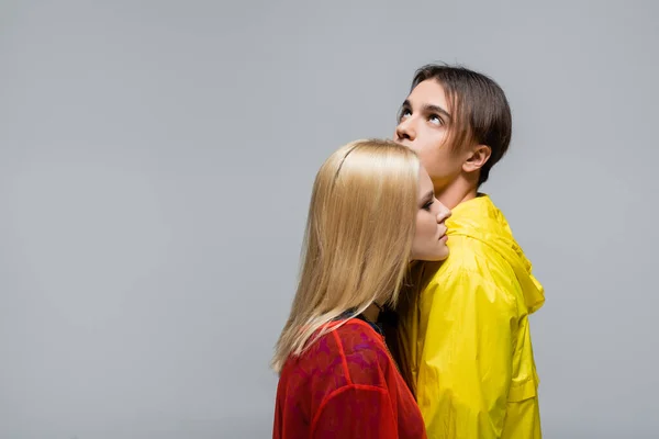 Blonde Frau steht neben Freund in Windjacke isoliert auf grau — Stockfoto