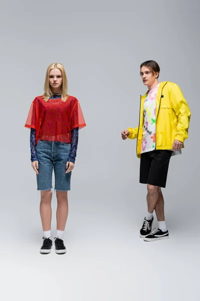 Stylish young man in yellow windbreaker looking at girlfriend on grey background — Foto stock