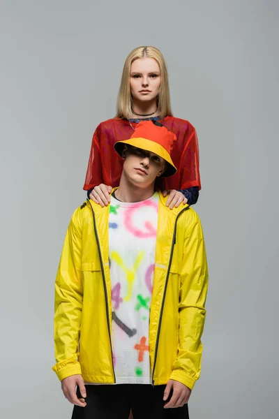 Blonde woman touching boyfriend in windbreaker and panama hat isolated on grey — Foto stock