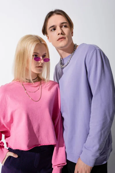 Stylish couple in sweatshirts looking away isolated on grey — Stock Photo