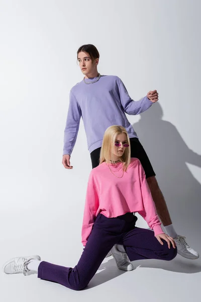 Full length of stylish couple in sweatshirts posing on grey background — Stock Photo