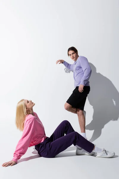 Full length of stylish young couple posing on grey background with shadow — Stock Photo