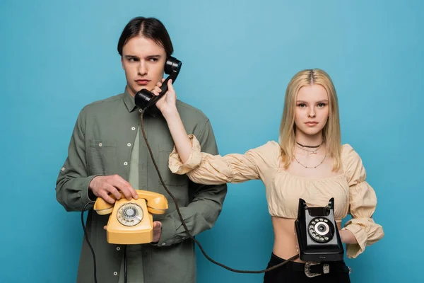 Stylish woman in blouse holding telephone handset near boyfriend isolated on blue — Stock Photo