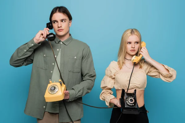 Stylish couple talking on vintage telephones isolated on blue — Foto stock