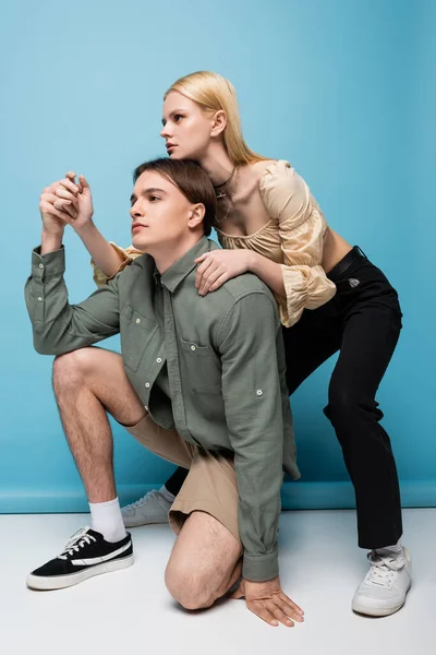 Pretty blonde woman hugging stylish boyfriend while posing on blue background — Stockfoto