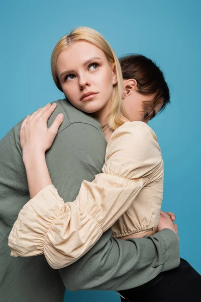 Pretty blonde woman hugging boyfriend isolated on blue - foto de stock