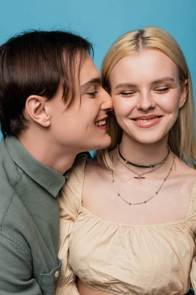 Homme souriant perdre à blonde copine avec les yeux fermés isolé sur bleu — Photo de stock