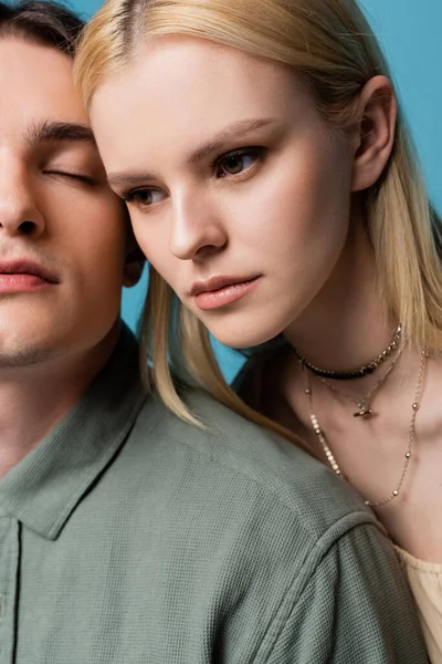 Pretty blonde woman looking away near boyfriend isolated on blue - foto de stock