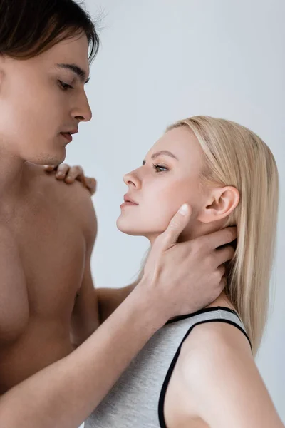 Вид сексапильного мужчины, трогающего блондинку на сером — стоковое фото