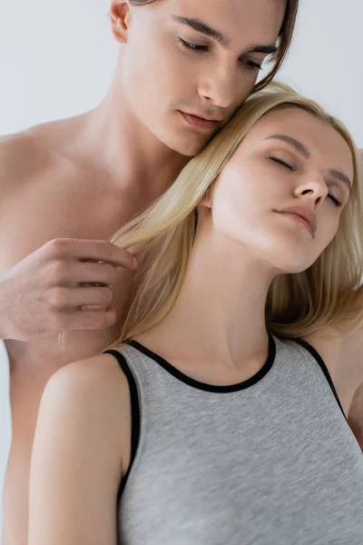 Без сорочки чоловік торкається волосся блондинки подруги ізольовані на сірому — стокове фото