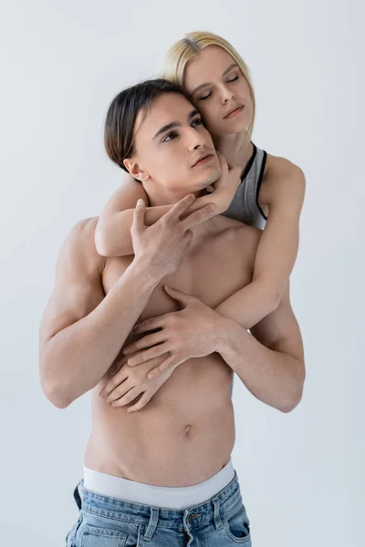 Jovem loira mulher abraçando sexy namorado no jeans isolado no cinza — Fotografia de Stock