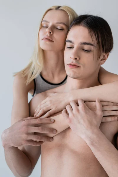 Retrato de mujer abrazando novio sin camisa aislado en gris - foto de stock