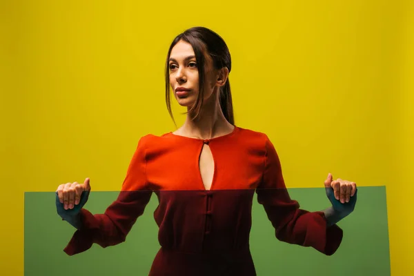 Stylish young woman in red dress holding glass isolated on green — Photo de stock