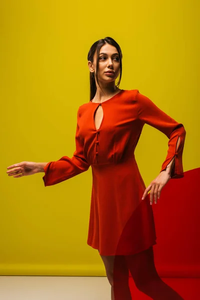 Elegante giovane donna in abito rosso in possesso di vetro forma rotonda su verde — Foto stock