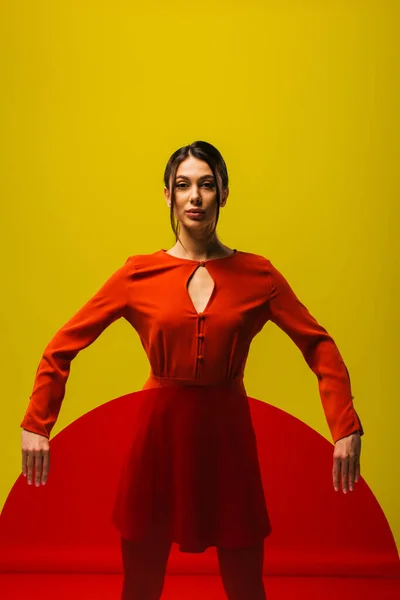 Stylish young model in red dress holding round shape glass isolated on green — Foto stock