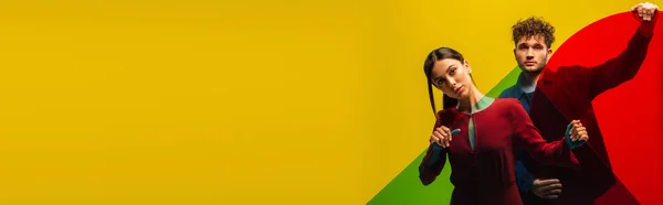 Trendy man and fashionable woman holding different shapes glass while posing isolated on yellow, banner — Stockfoto