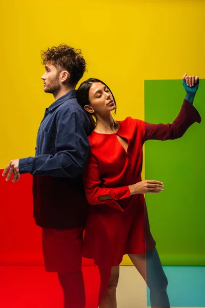 Trendy man and brunette woman holding different shapes glass while posing isolated on yellow — Foto stock