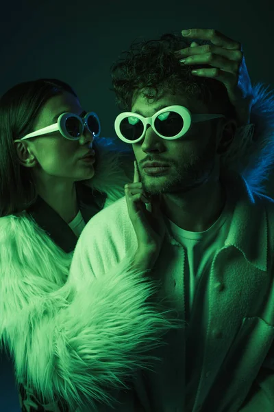 Retrato de modelos na moda em óculos de sol e roupas da moda posando em azul escuro — Fotografia de Stock