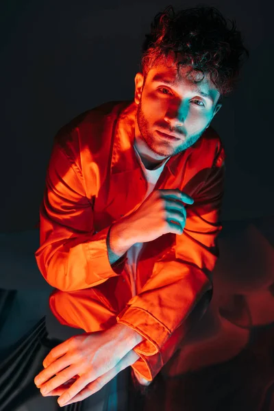 Portrait of curly and young man in orange shirt posing on blue - foto de stock