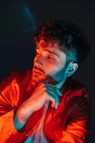 Portrait of curly and young man in orange shirt looking away on blue - foto de stock