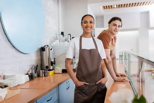 Smiling interracial sellers looking at camera in confectionery — Photo de stock