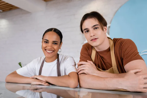 Smiling interracial sellers looking at camera in confectionery — Fotografia de Stock