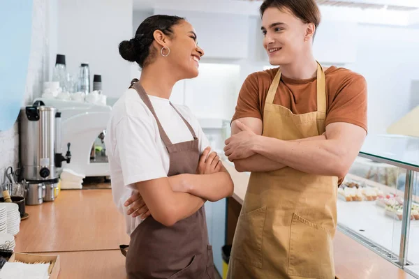 Positive multiethnic sellers in aprons talking in confectionery — Fotografia de Stock