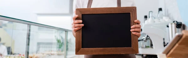 Cropped view of african american seller holding chalkboard in confectionery, banner — Stockfoto