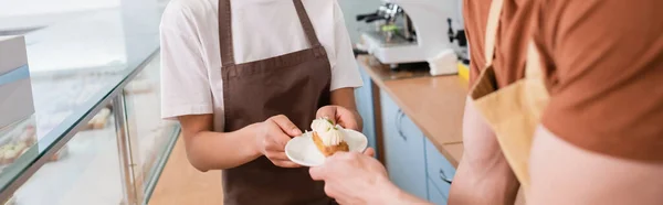 Ausgeschnittene Ansicht eines afrikanisch-amerikanischen Verkäufers, der seinem Süßwarenkollegen ein Dessert gibt, Banner — Stockfoto