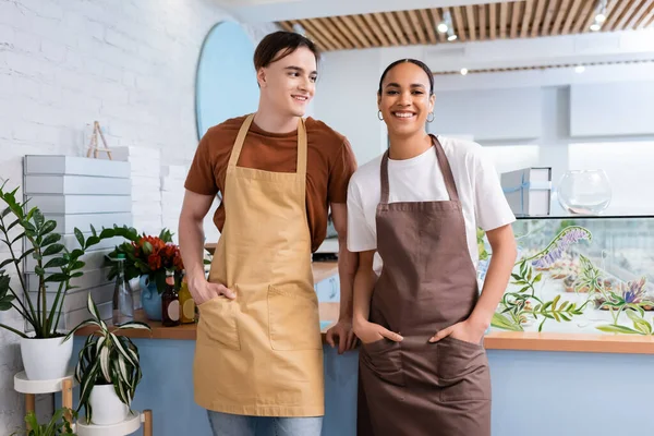 Smiling seller looking at african american colleague in confectionery — Stockfoto