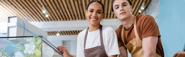 Positive multiethnic workers of sweet shop looking at camera, banner — стоковое фото