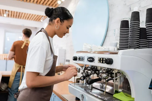 Afrikanischer Barista kocht Kaffee in der Nähe von Maschine in Süßwaren — Stockfoto