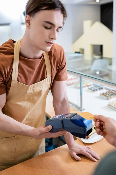 African american customer paying with credit card near salesman in confectionery — стокове фото