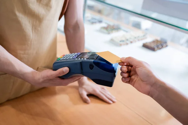 Cropped view of salesman holding payment terminal near african american customer in sweet shop — Photo de stock