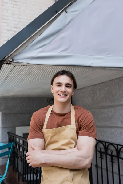 Cheerful seller looking at camera near confectionery on urban street — Stock Photo