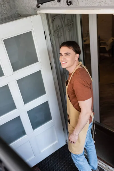 High angle view of smiling seller looking at camera near entrance of sweet shop - foto de stock