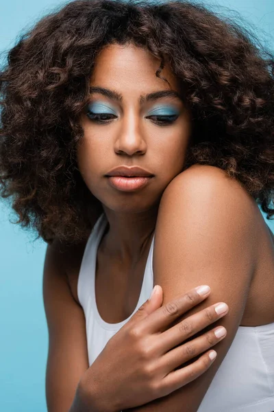 Портрет кучерявої афроамериканської жінки з яскравим макіяжем ізольовано на синьому — стокове фото