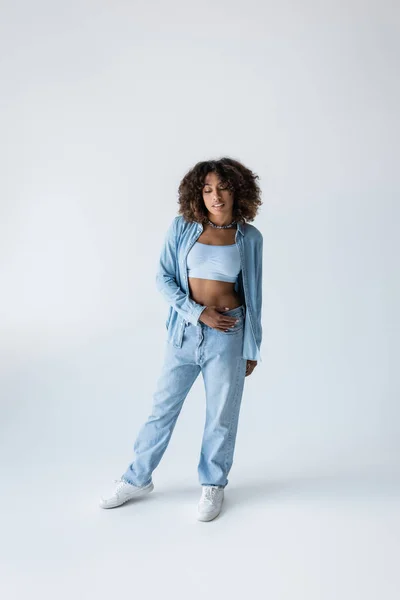 Full length of african american woman in white sneakers and blue denim clothing on grey background — Fotografia de Stock