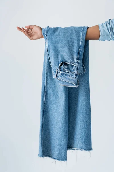 Cropped view of african american woman holding blue jeans isolated on grey - foto de stock