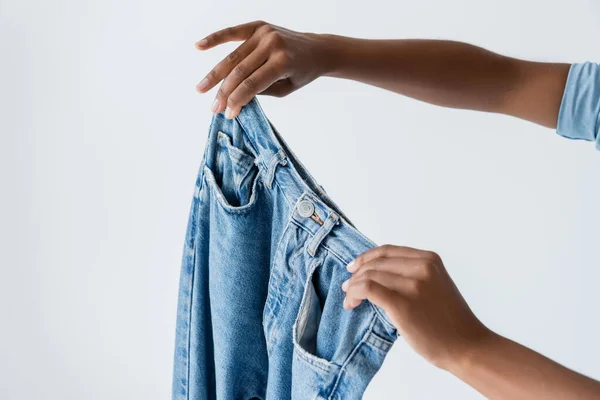 Cropped view of african american woman showing jeans isolated on grey — стоковое фото