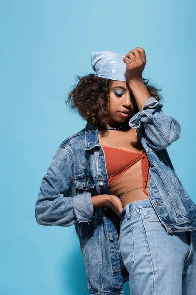 African american woman in swim bra and jacket obscuring face with hand on blue background — стокове фото