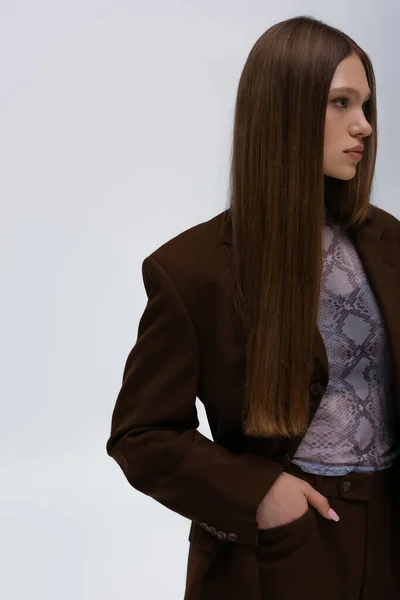 Pretty teenage model in brown high-quality suit posing with hand in pocket isolated on grey — Fotografia de Stock