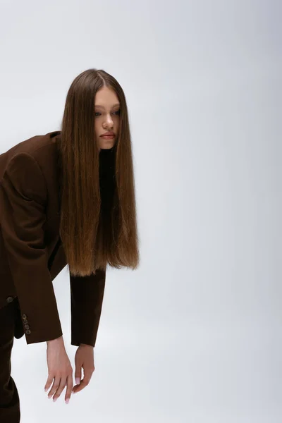 Pretty teenage model in brown high-quality suit posing isolated on grey — Photo de stock