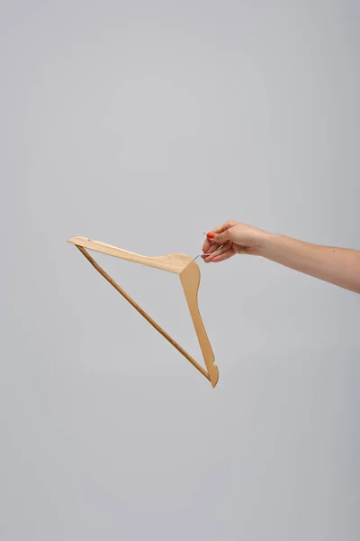 Cropped view of woman holding wooden hanger isolated on grey - foto de stock