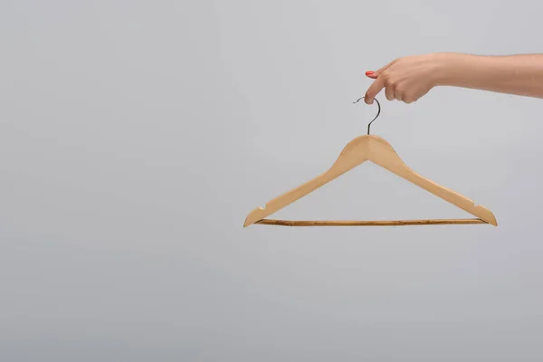 Partial view of model holding wooden hanger isolated on gray — Stock Photo