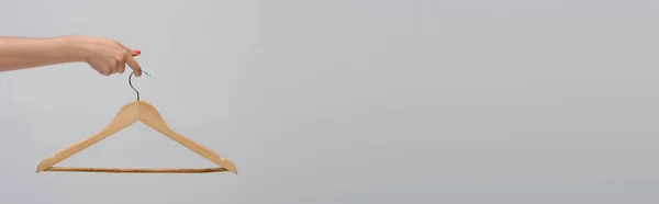 Partial view of model holding wooden hanger isolated on gray, banner — Stockfoto