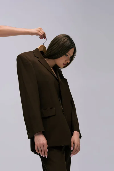 Woman holding hanger with teenage model in recyclable blazer isolated on grey — Stockfoto